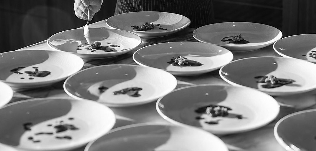 A course being finished by hand with a spoon, the same plate repeated down the length of the pass
